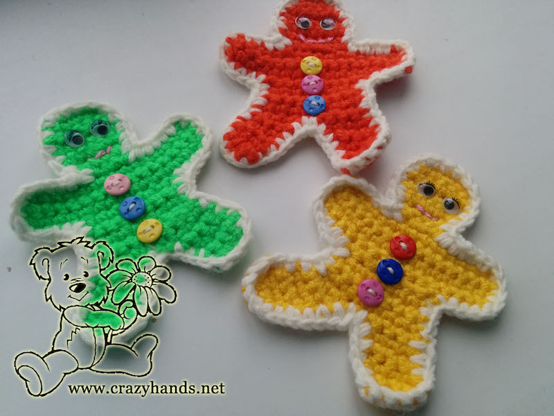 three crochet gingerbread men - one green, one yellow, and one red