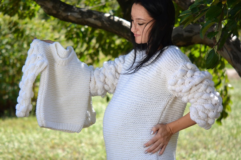 woman model wears oversized knit sweater with bobbles and holds matching sweater for baby