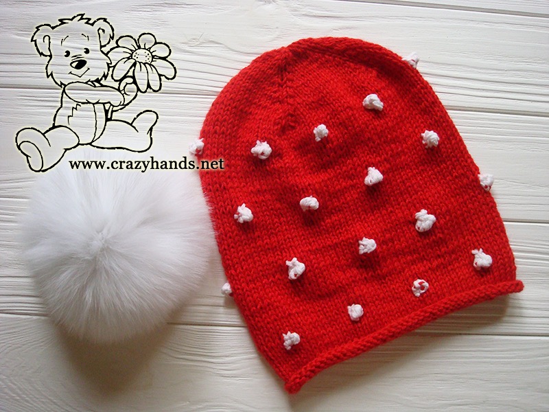 Santa-Style Knit Hat and Fur Pom Pom Beside Each Other