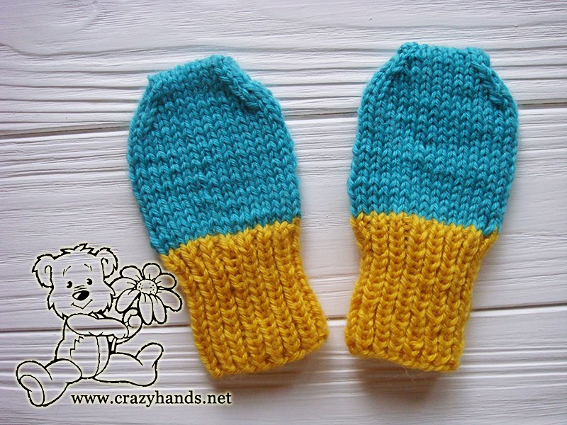 a pair of blue and yellow baby knit thumbless mittens