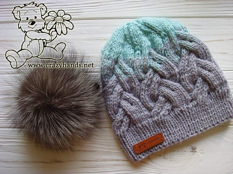 two-color cable knit hat decorated with fur pom pom