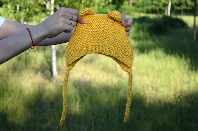 front view of the teddy bear baby knit bonnet made with yellow yarn