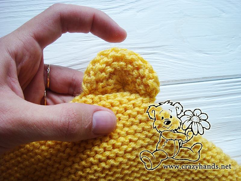 sewing teddy bear's ear to the baby knit bonnet