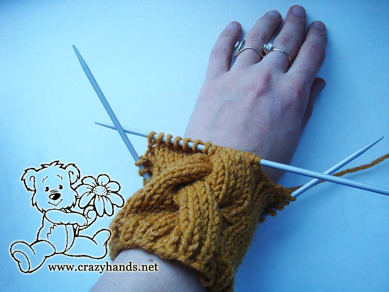 knitting ribbing of long cable mitten on female hand