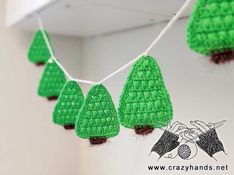a set of crochet christmas trees assembled in a garland