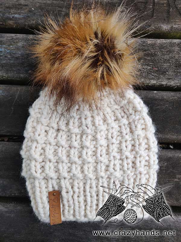 finished vortex super bulky knit hat decorated with faux fur pom pom and leather strip