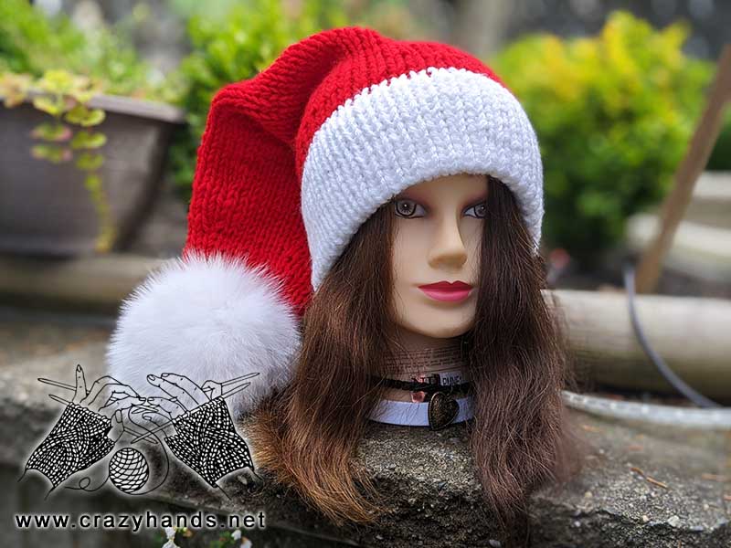 knit santa hat with white brim, red body, and white fur pom pom