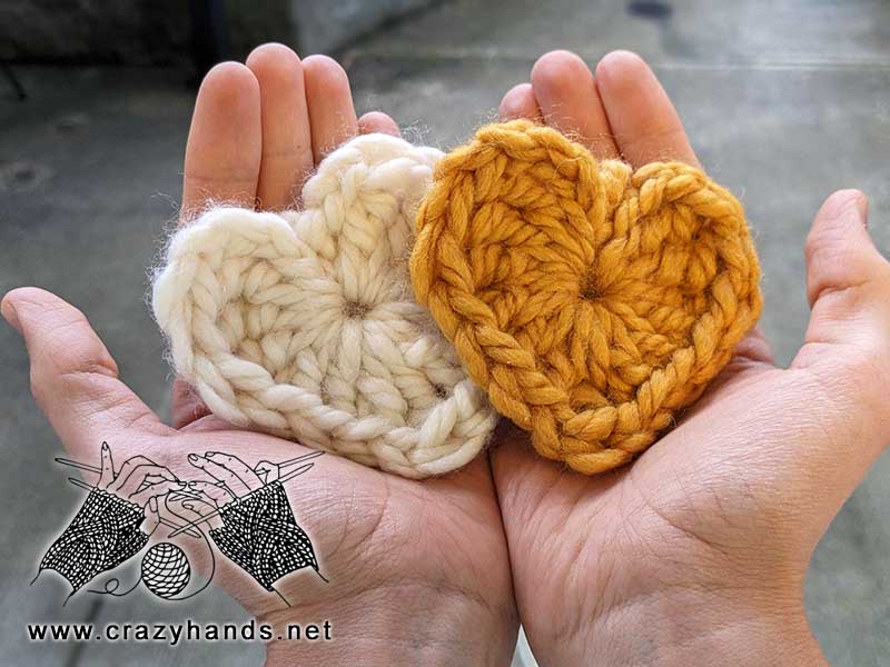 two chunky crochet hearts - one made with white yarn and another one with golden yarn
