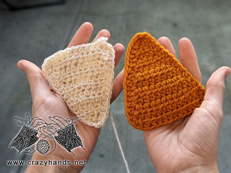 two crochet isosceles triangles held on the hands - one yellow and one white