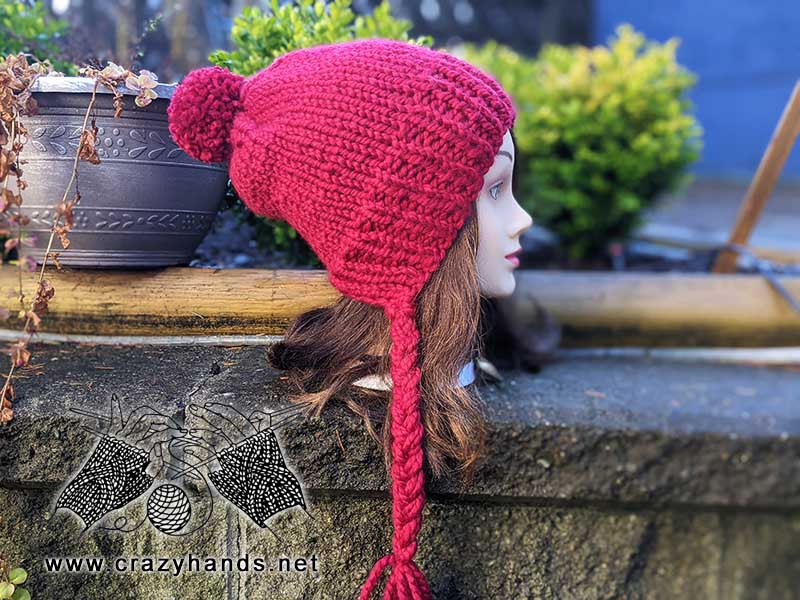 knit riding hood hat with braided ties on the mannequin