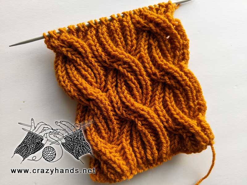 cable knit scarf on straight needles made with orange yarn