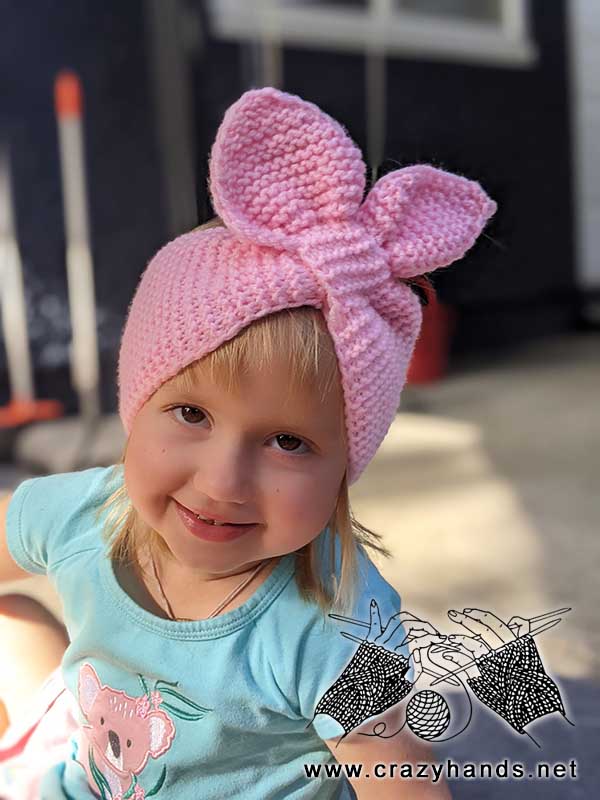 baby girl wears pink knit headband with bunny ears