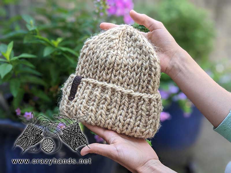 super bulky knit hat is held in hands with nature in the background