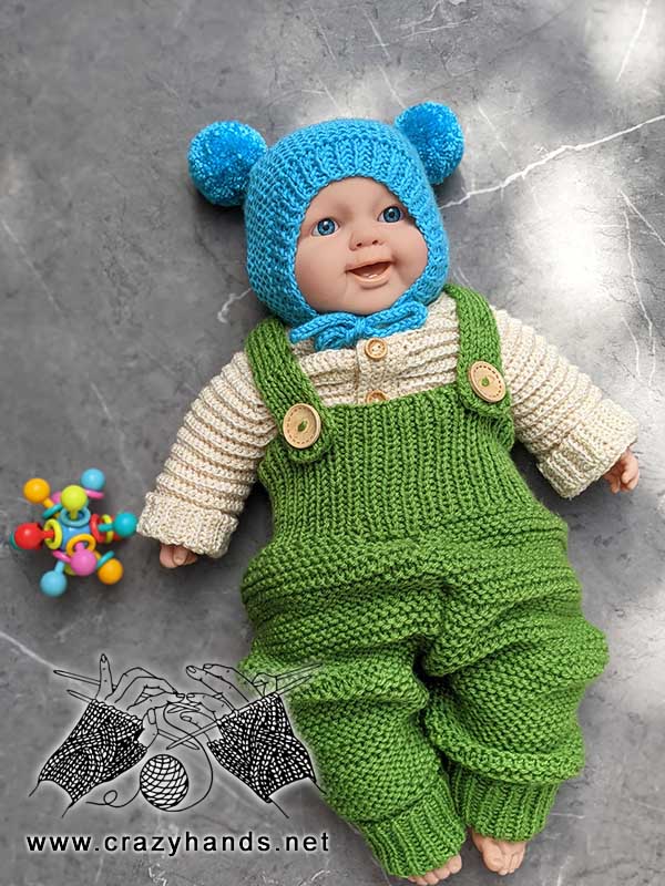 baby doll wears knit bonnet, knit cardigan, and knit jumpsuit