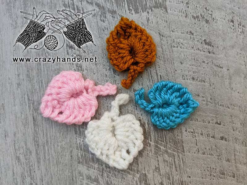 four crochet small leaves - white, pink, brown, and blue