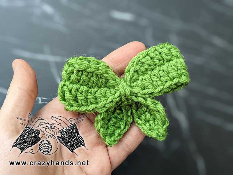 green crochet bow butterfly on a hand