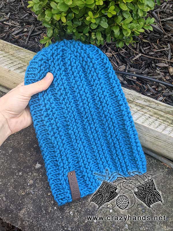 shot of a slouchy knit hat made on circular needles on the hand