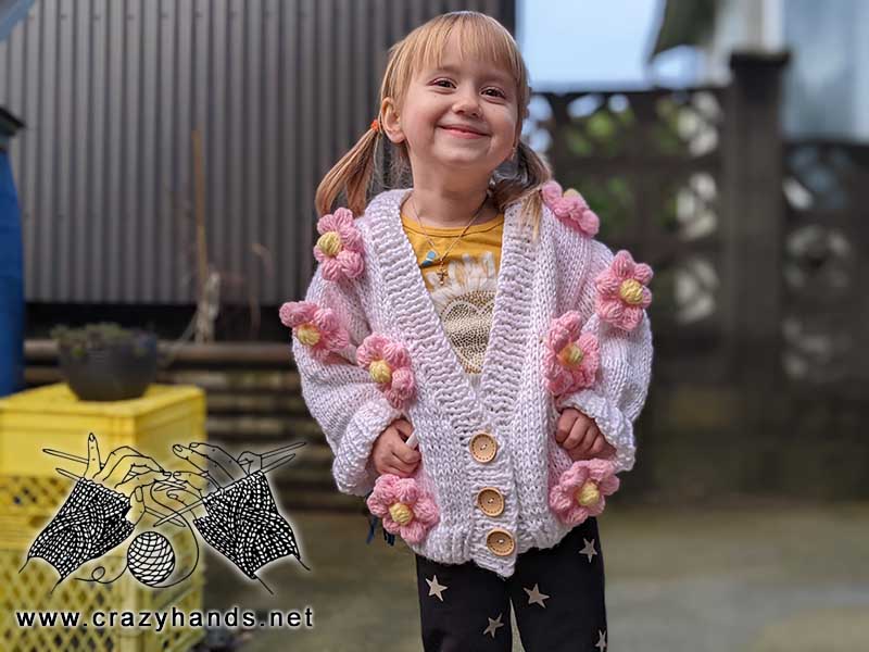 4 years old girl wears knit cardigan with crochet decor flowers