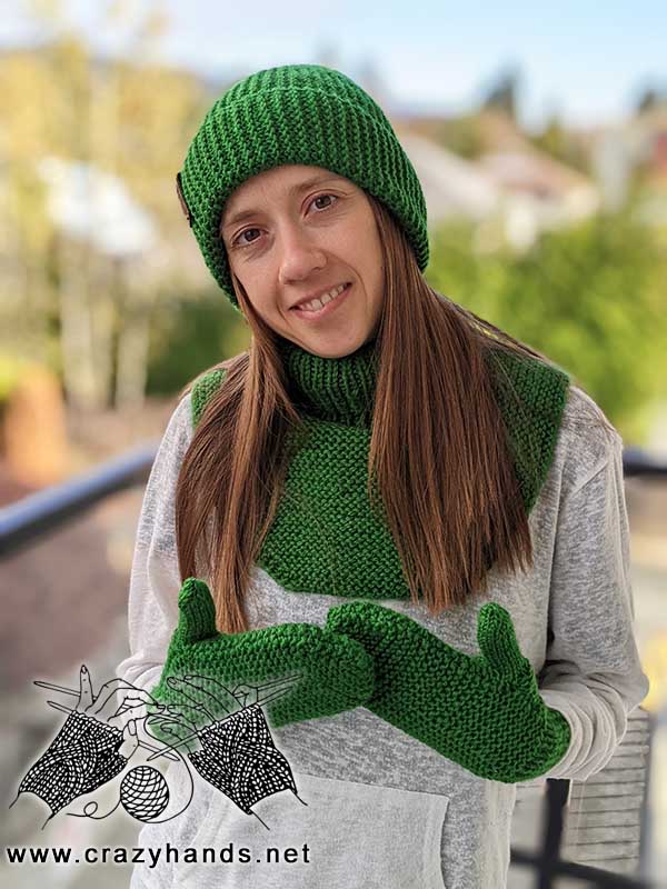 female model wears a knit dickey, knit mittens, and a flat knit hat