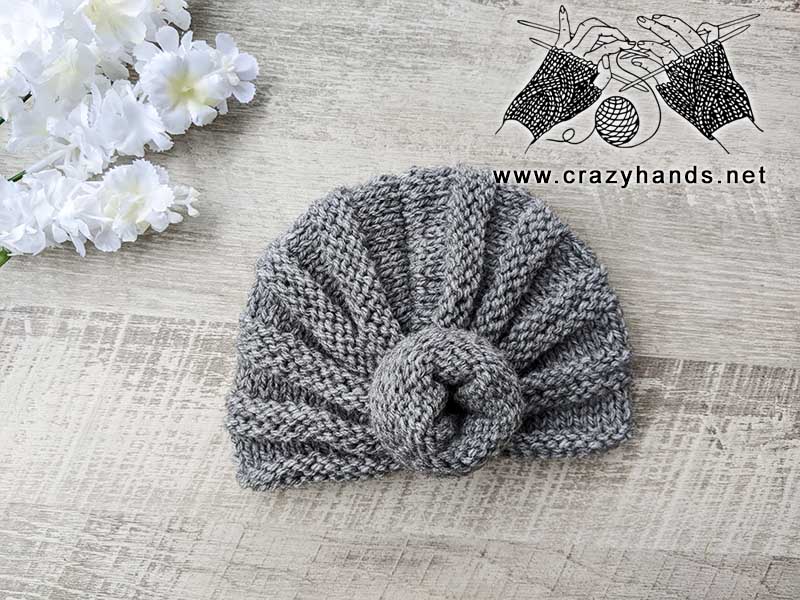 baby knit turban hat with a decor know on the front