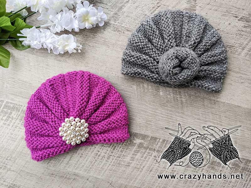 two baby knit turban hats - one decorated with a brooch and another one with a knot