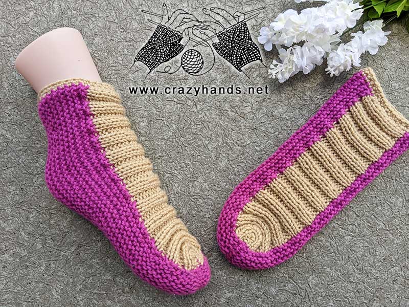 knit flat two-color slippers - one sock is shown on a mannequin foot, and another sock lays on a flat surface