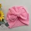 pink knit baby turban hat with bow laying next to sunflowers