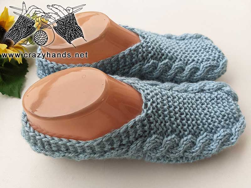 close up view of a pair of flat knit cable slippers on the mannequin feet