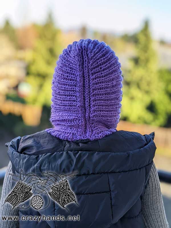 backside view of a knit ribbed hooded cowl on a female model