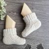 knit baby socks made in round on the mannequin's feet