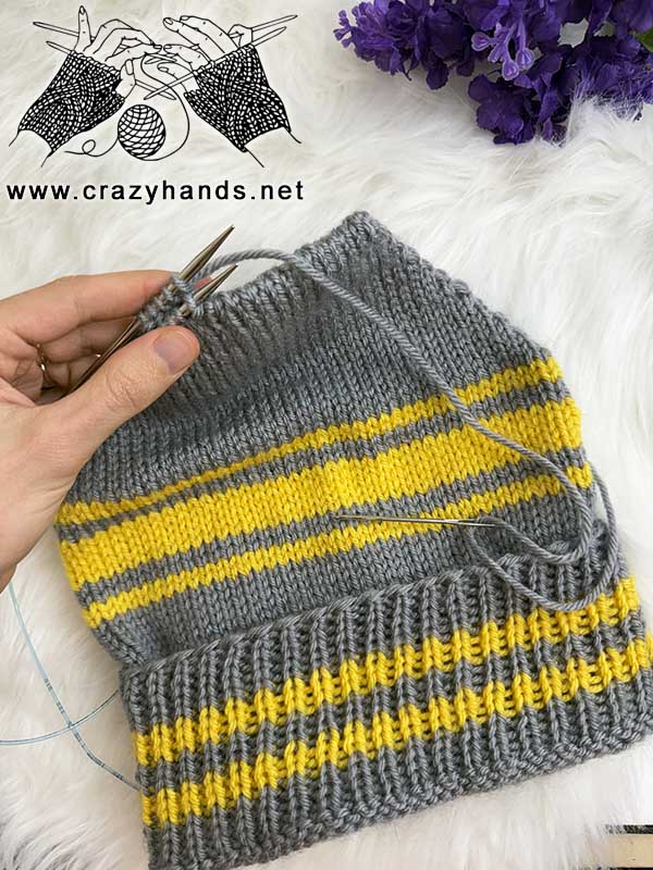 finishing the crown of a golden striped knit beanie