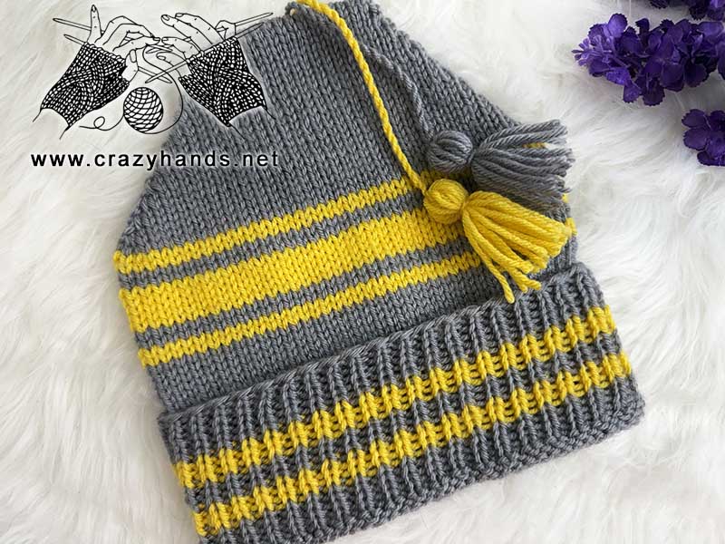 golden striped knit beanie with a ribbed brim and two tassels